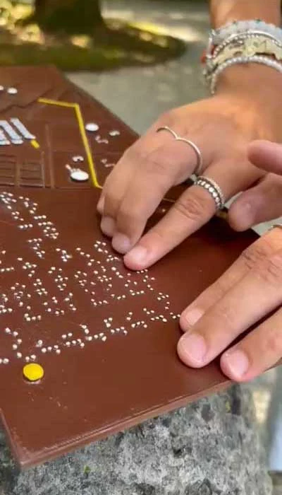 Hands exploring a tactile surface with Braille dots and raised features
